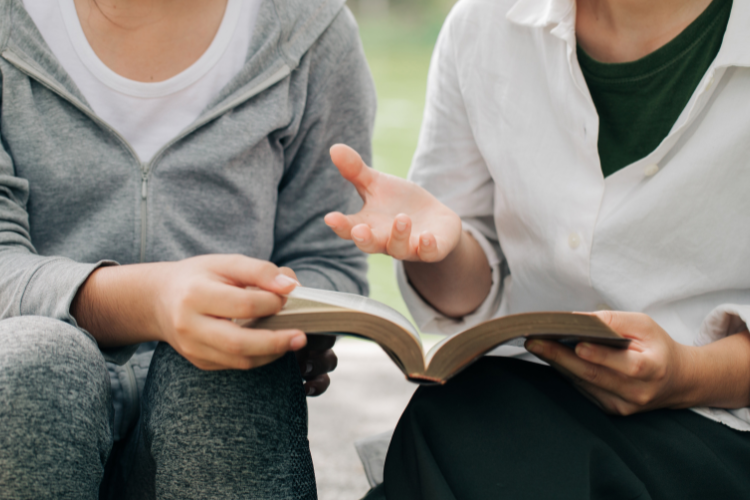 Kaksi naista lukee raamattua ja rukoilee.