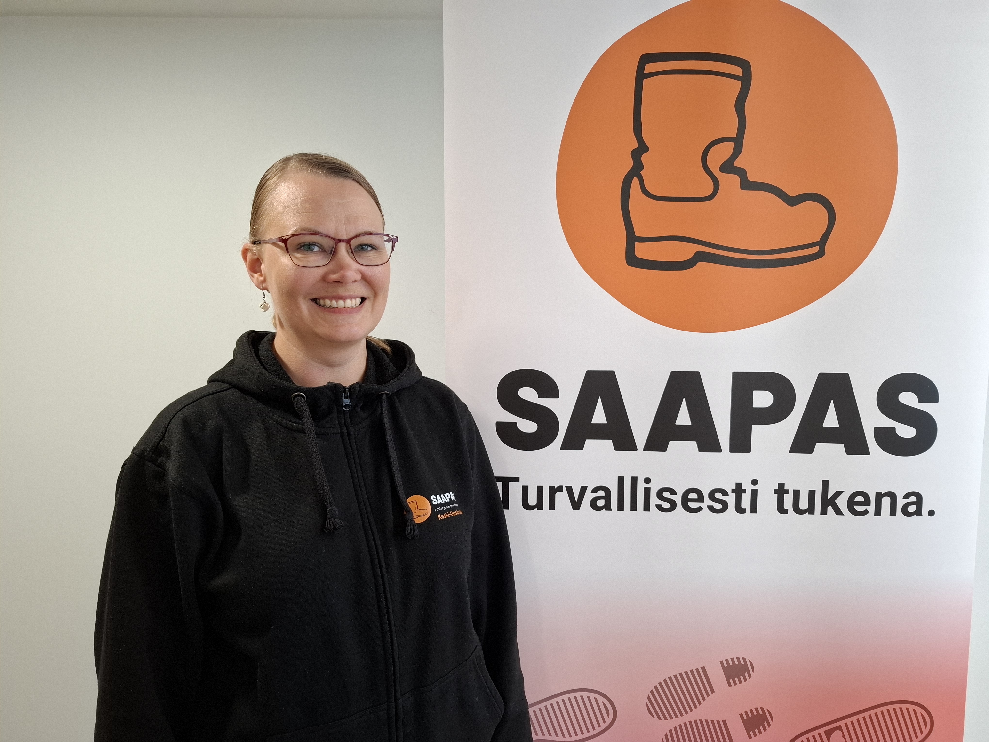 Airi Laurila Saappaasta kertovan esitteen edessä.