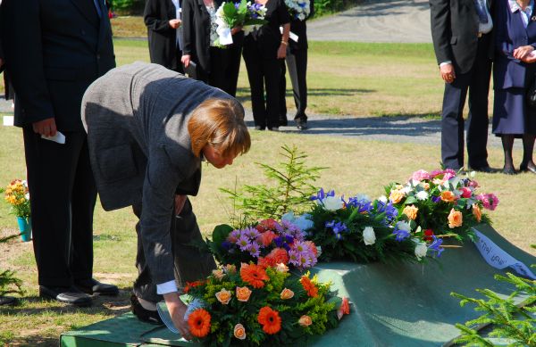 hautajaisvieraat laskevat kukkalaitteita haudalla.