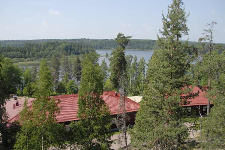 Nuottakodon majoitusrakennus rinteeltä kuvattuna, taustalla Poikkipuoliainen-järvi.