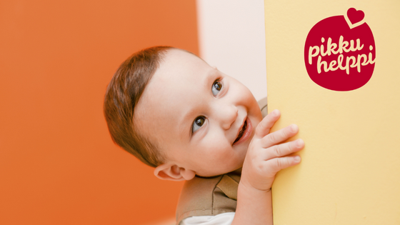 hymyilevä lapsi kurkistaa seinän takaa, pikkuHelppi logo.