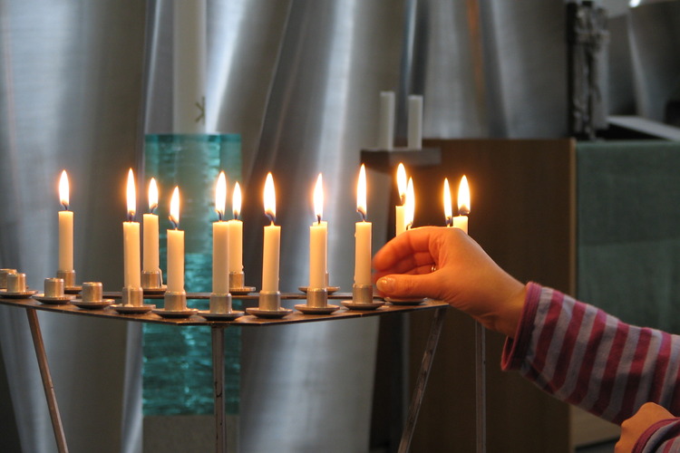 Nuori asettamassa elämänkaari kynttilöitä kastetuille, menehtyneille sekä avioliittoon aikoville.