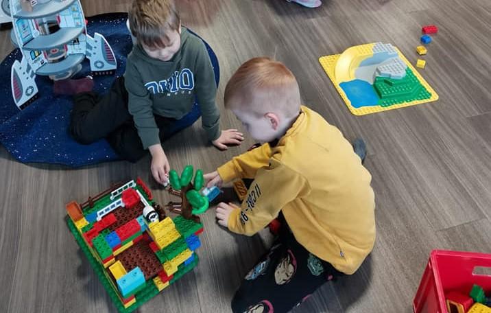 Koululaiset rakentelevat legoja lattialla.