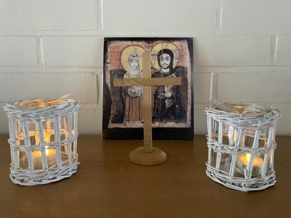 Ikoni, risti ja kaksi kynttilää pöydällä. 