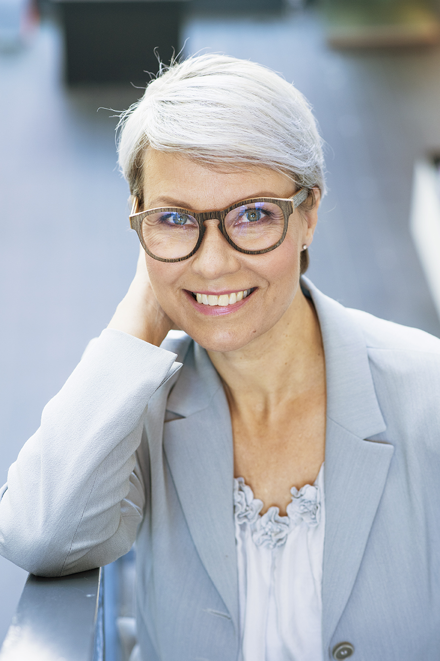 Senioritiistai Tuula Portin istuu sinisessä asussa, käsi poskella ja katsoo kameraan