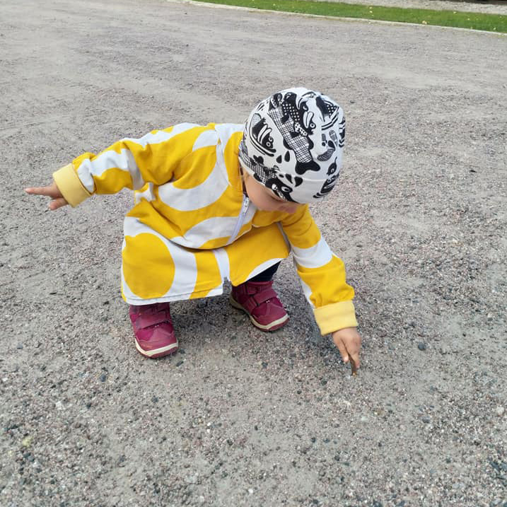Syksyn perheleiri lapsi keltainen takki päällä.