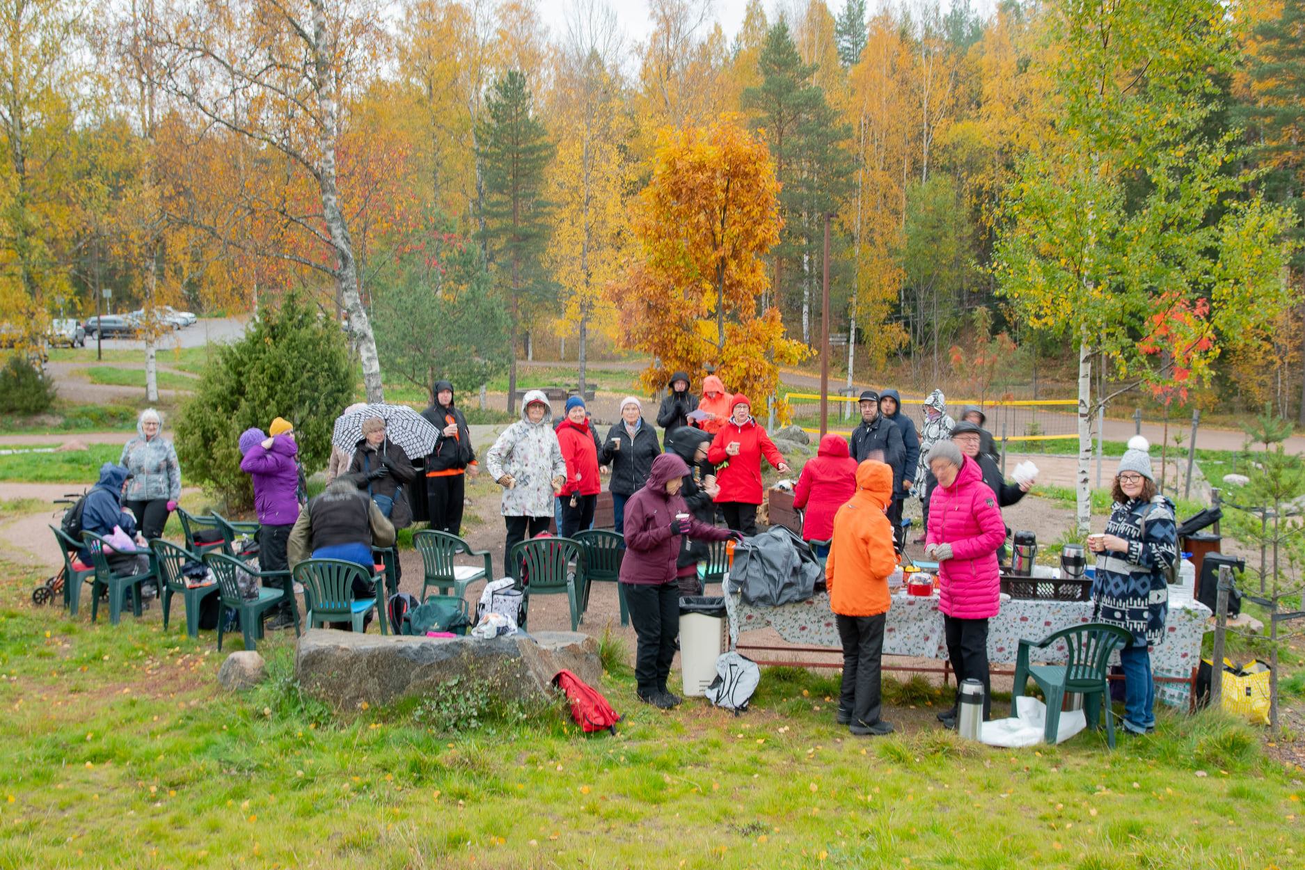 ihmisiä nuotion ääressä Keinukallion syksyisessä maisemassa.