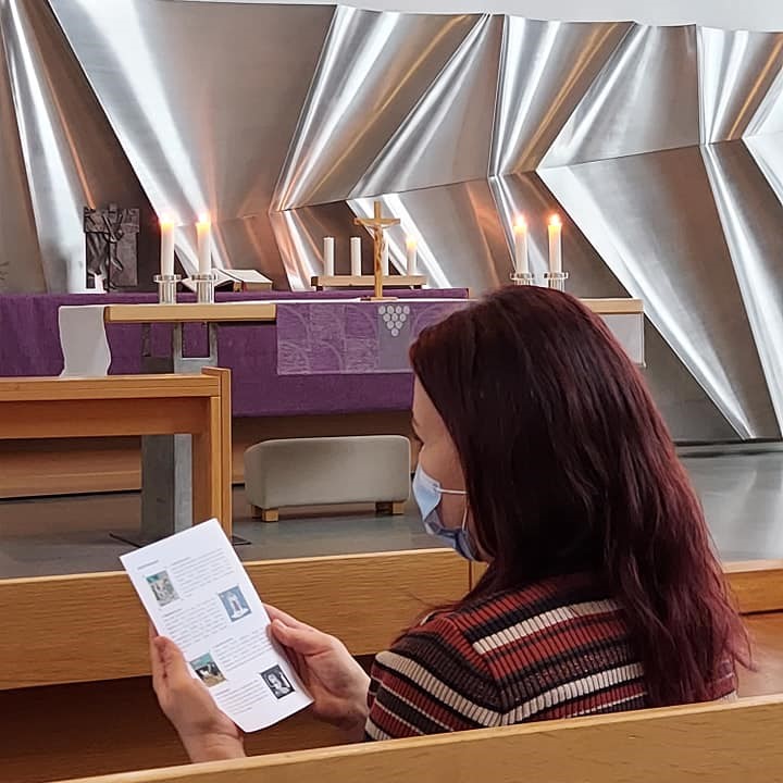 Nainen lukee rukouskorttia Keravan kirkon penkissä.