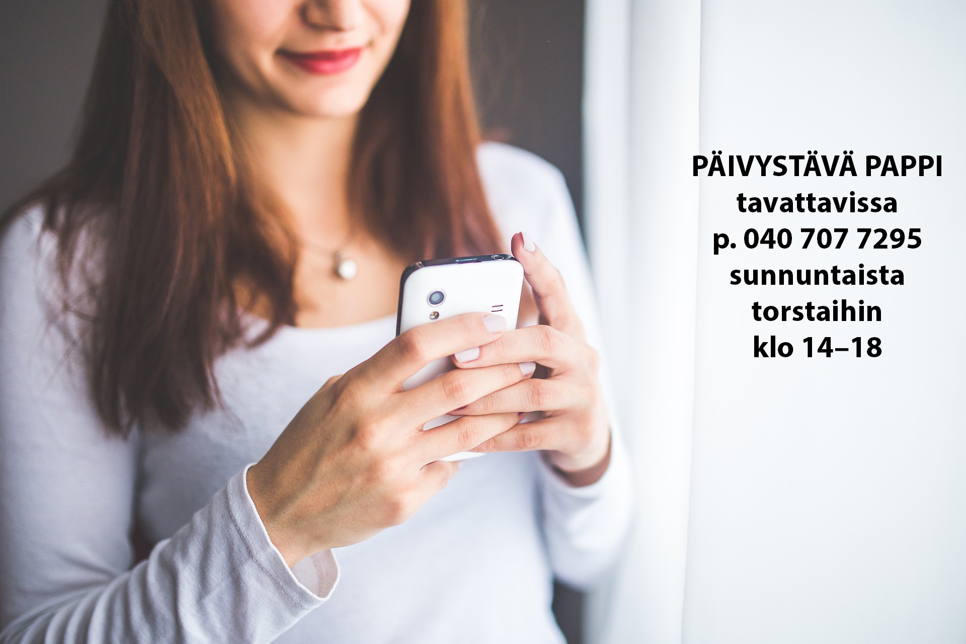 nainen kännykkä kädessä ja tekstinä päivystävän papin yhteystiedot