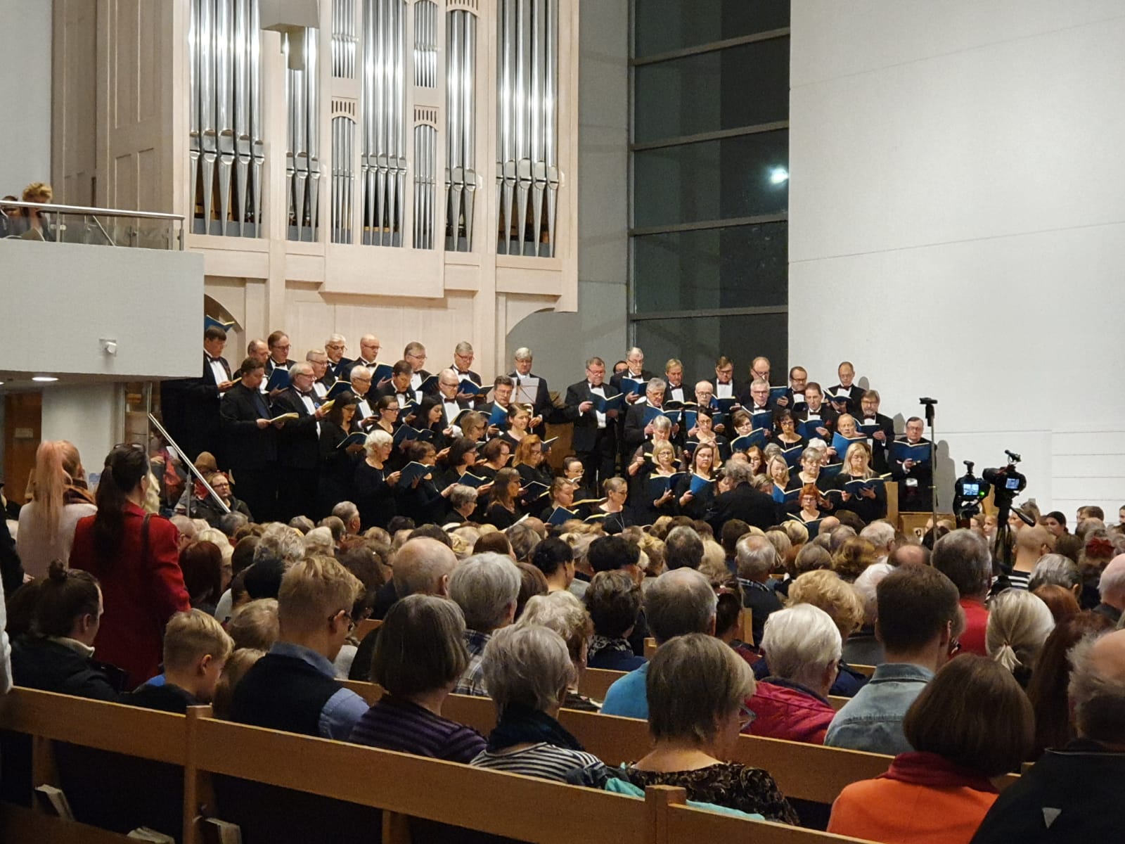 Keravan kirkko on täynnä konsertin kuulijoita. Taustalla Mozartin Requiemia laulavat kuorolaiset.