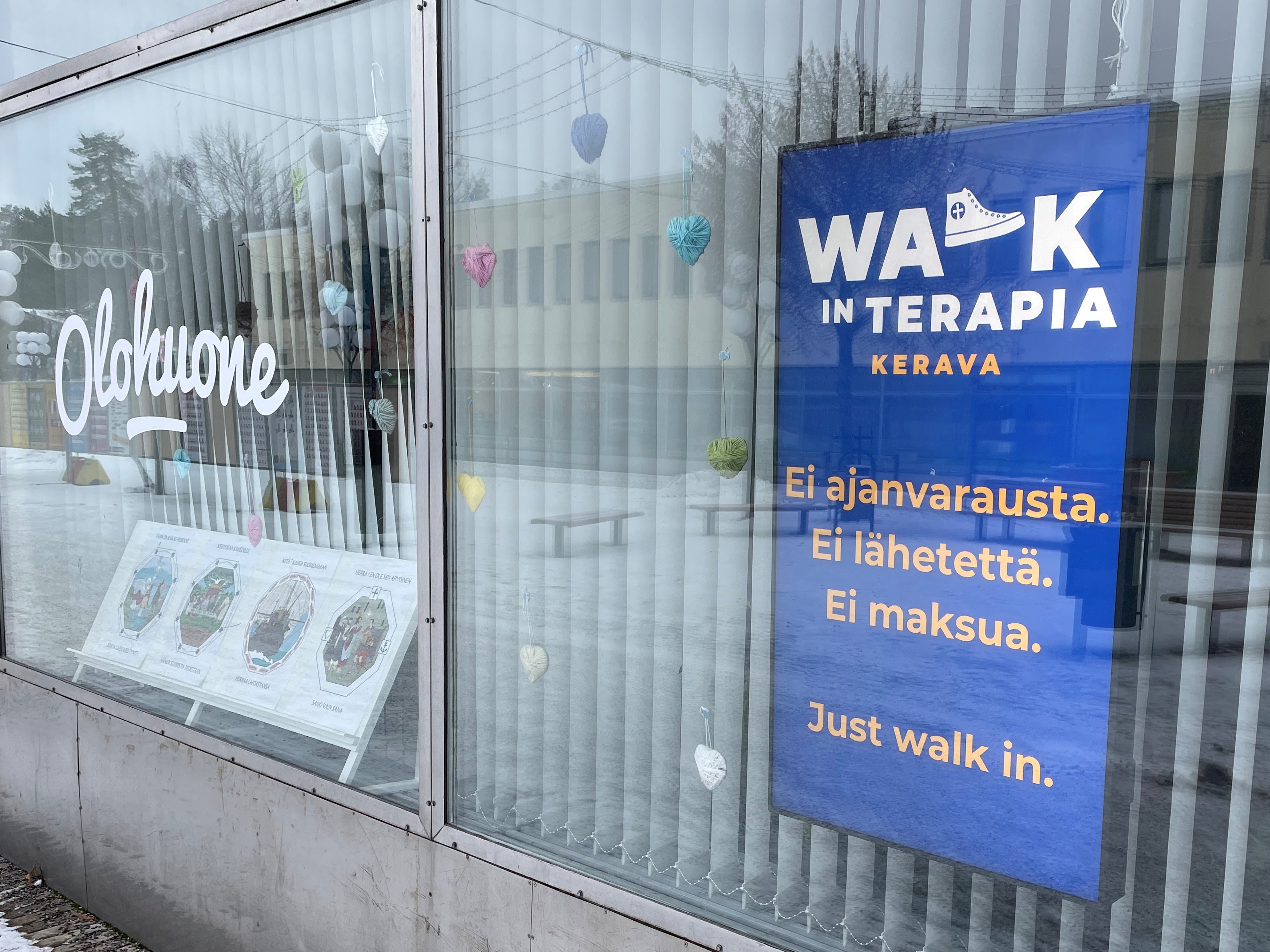 kuvassa Katupappilan ikkuna, jossa näkyy teksti Olohuone sekä näytöllä walk in -terapian mainos.