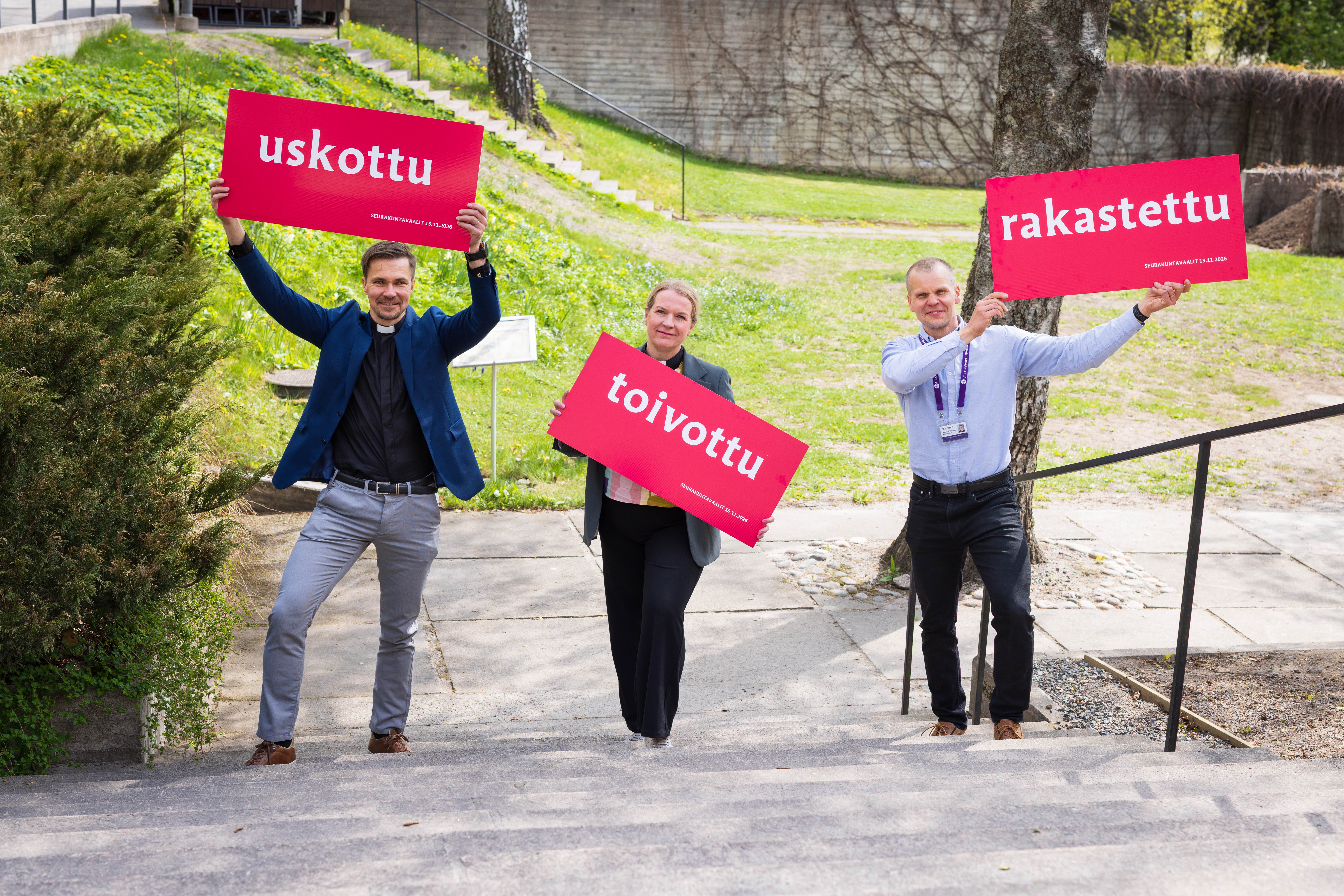 haastatellut kirkkoherrat käsissään uskottu-, toivottu-, rakastettu -kyltit