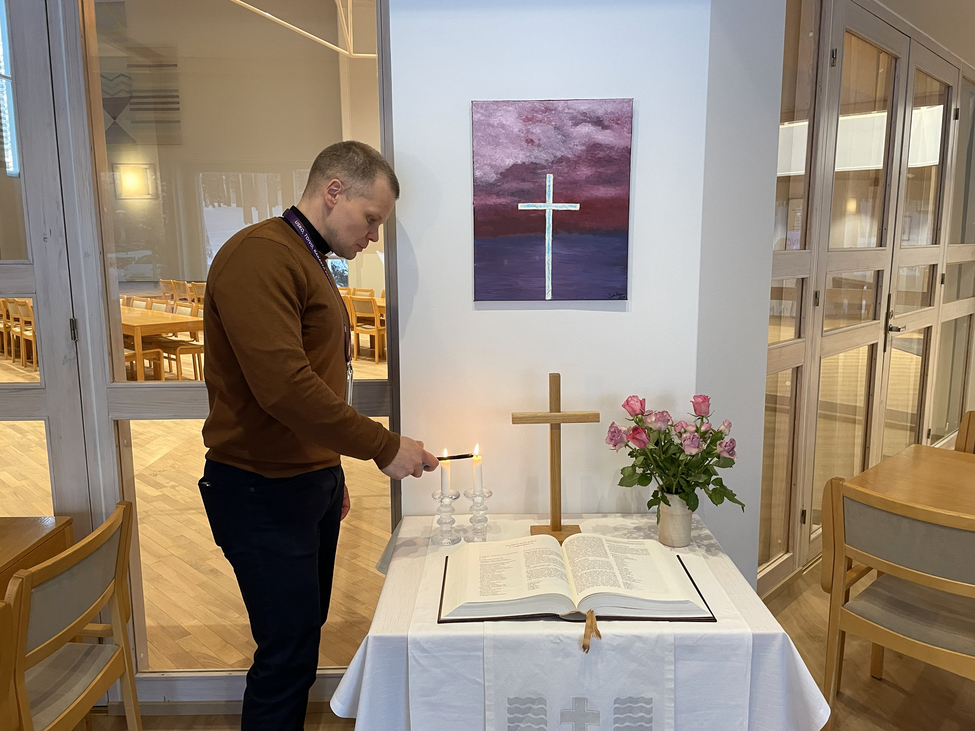 kirkkoherra sytyttää alttarin kynttilän. 